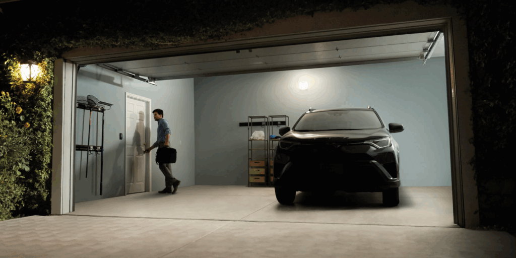 Garage door opened with LiftMaster smart garage openers, black car parked in the garage, and man with hand on door knob entering home