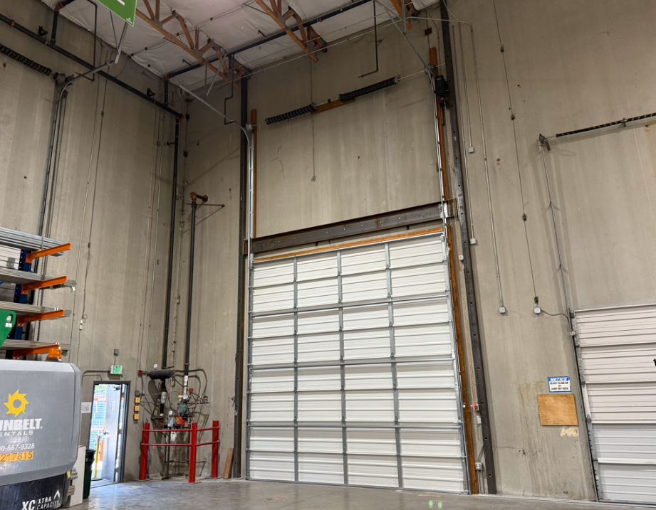 Inside of a garage with a tall white commercial garage door 