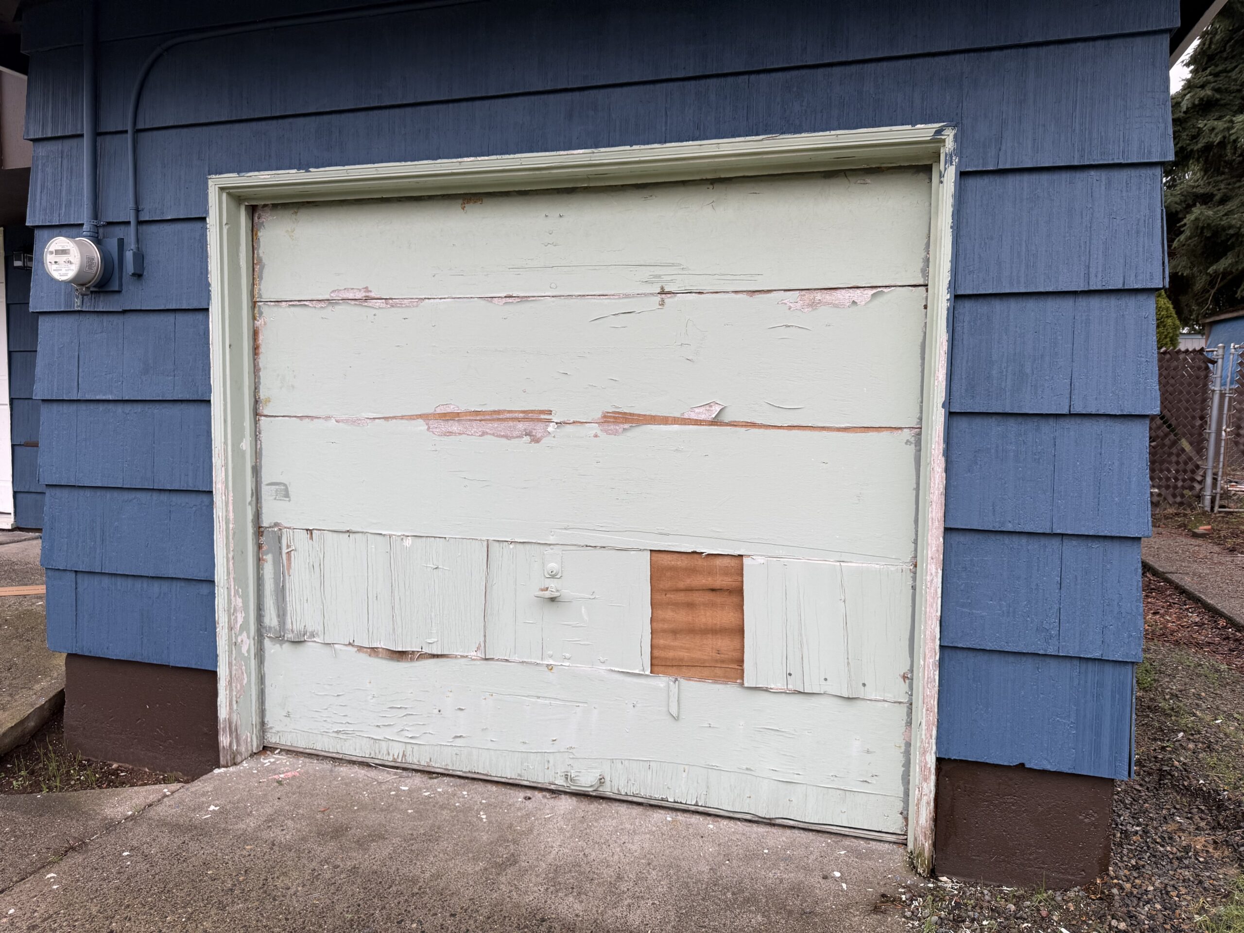 A white garage door with chipped paint and missing tiles in need of a residential garage door tune-up