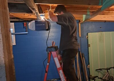 Worker on a ladder repairing a garage door opener